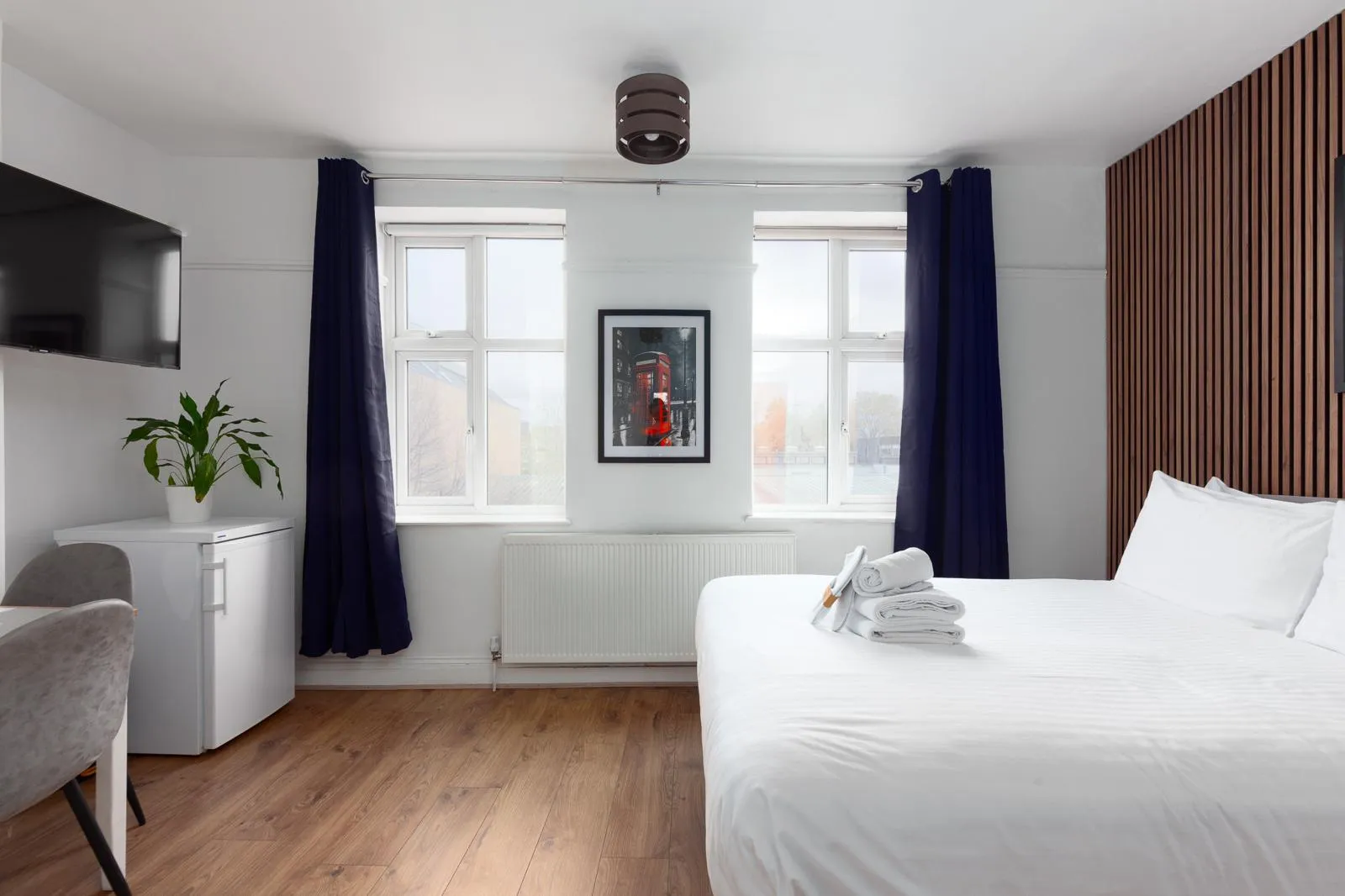 A serviced apartment with a double bed, smart TV and a wood-panelled feature wall