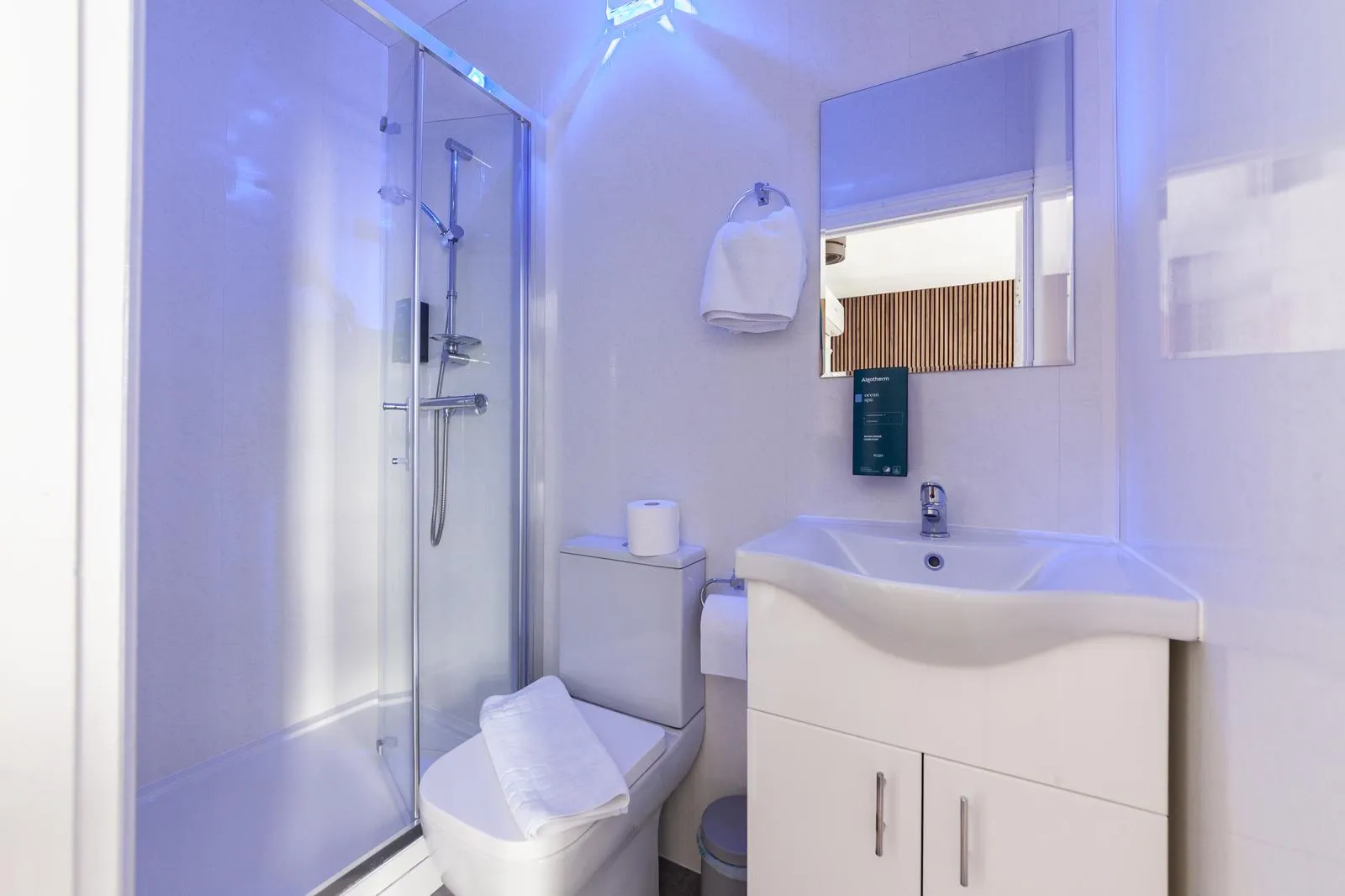 Private en-suite shower room with a wood-panelled wall and fresh towels