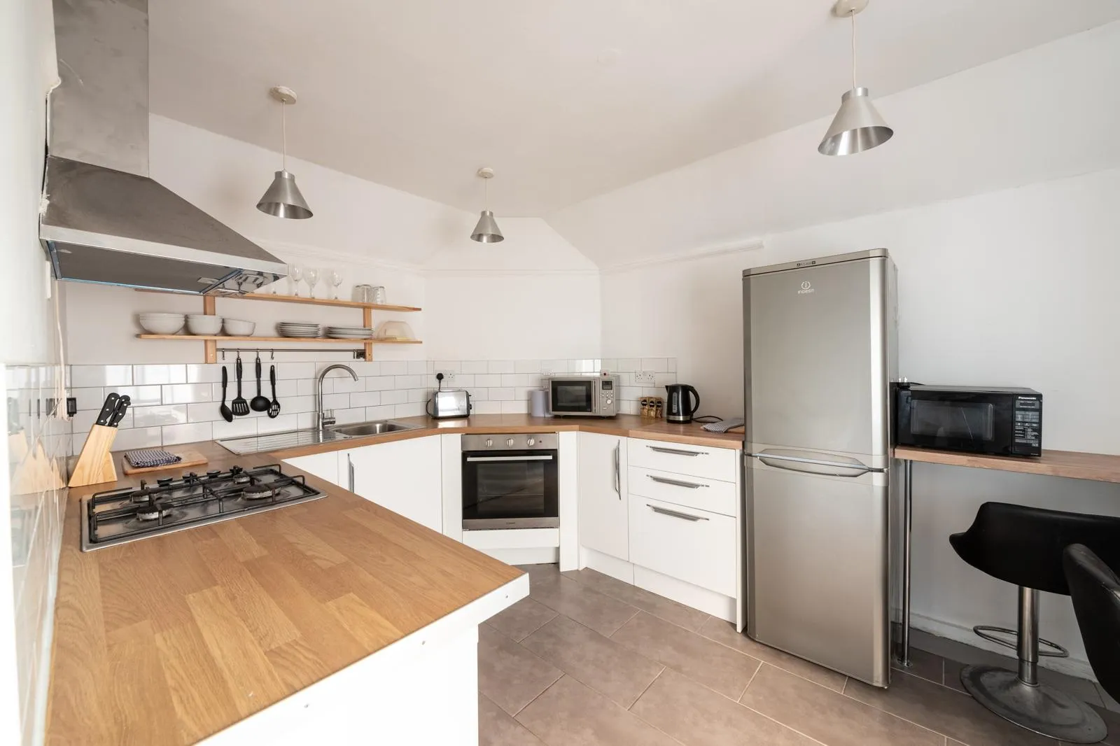 Fully fitted kitchen with a gas hob, oven, fridge-freezer and breakfast bar